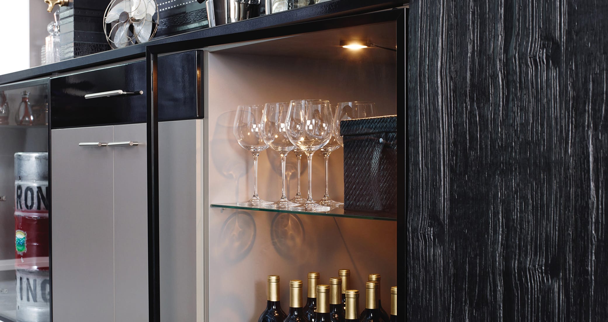 Wine bar in the home with open shelving, LED lighting, prep counter in dark wood grain finish by California Closets